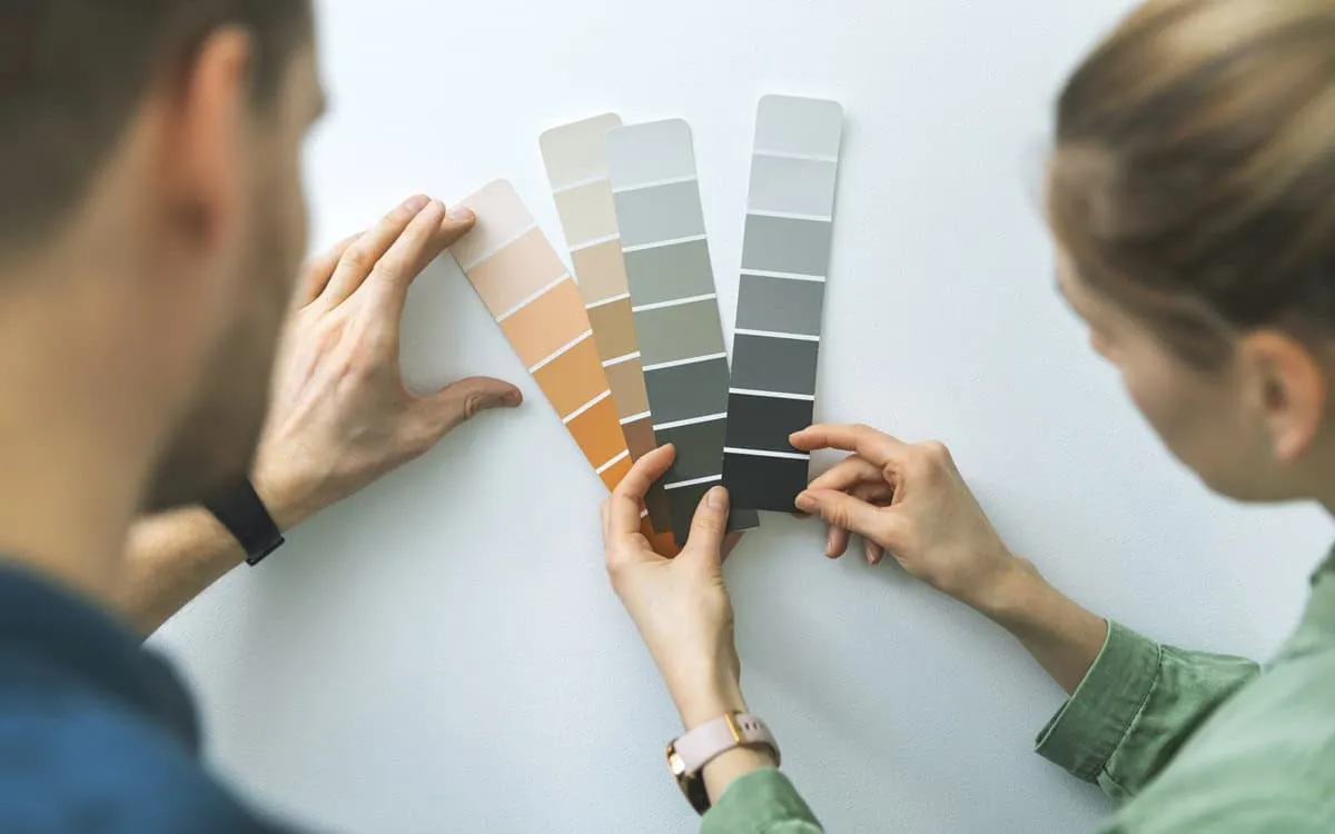 couple choosing neutral exterior house colors using color swatches